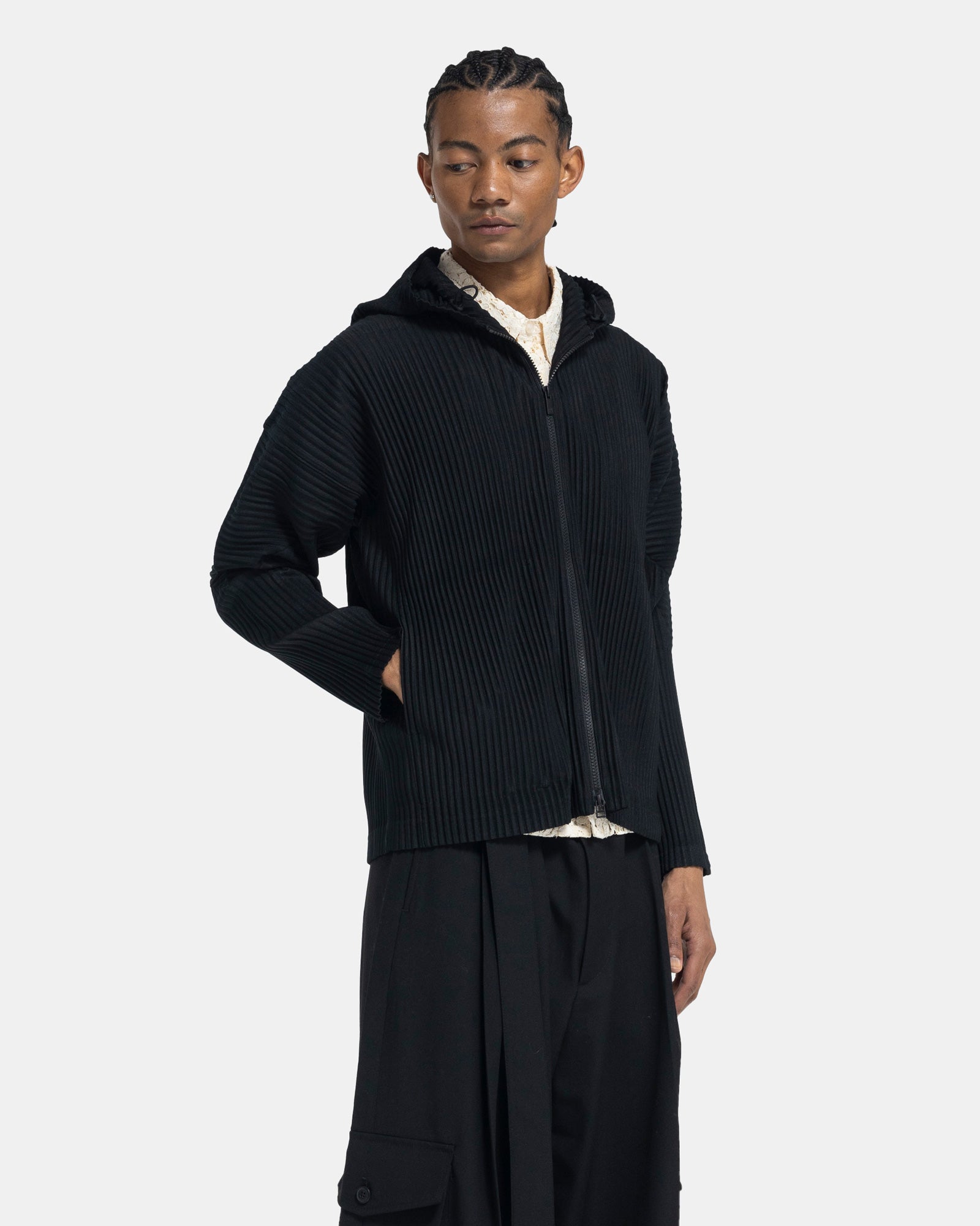 Male model wearing issey miyake homme plissé black pleated hoodie on white background