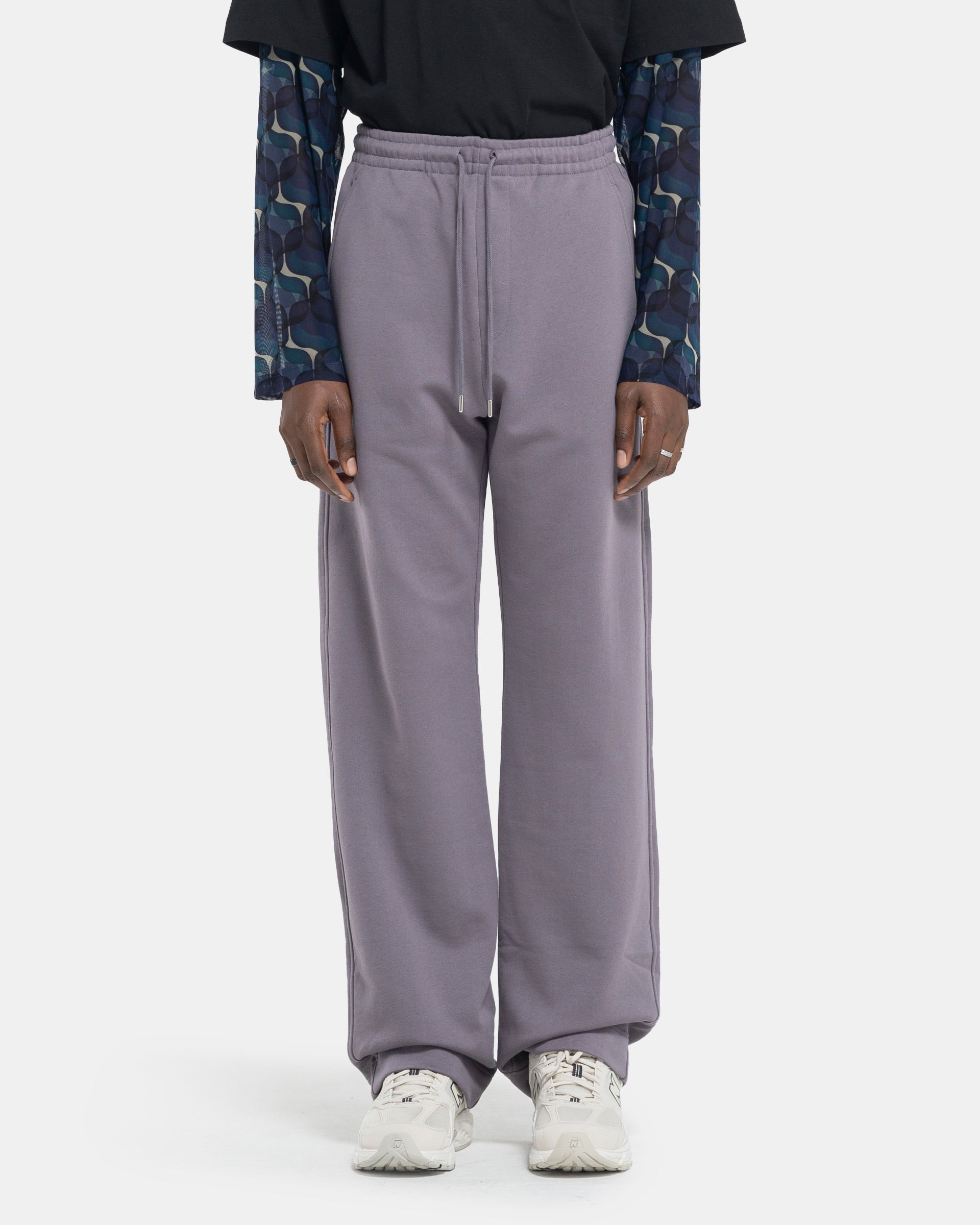 Model wearing Dries Van Noten Hamer Sweatpants in Pruple on a white background