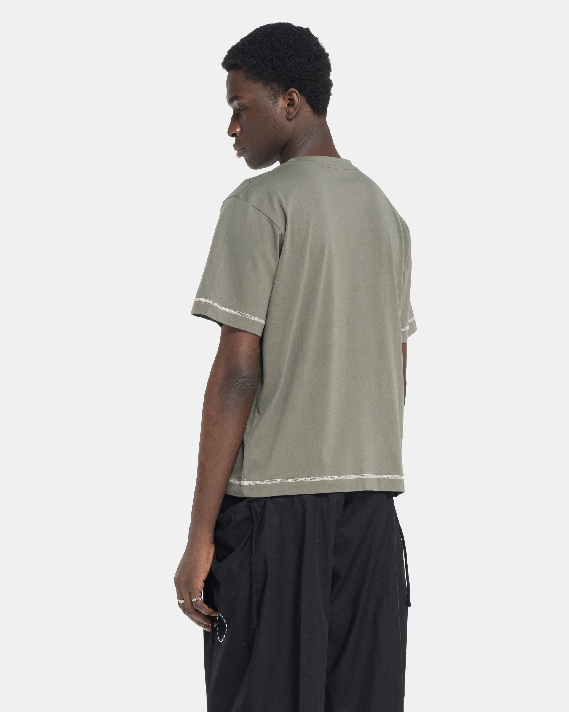 Model wearing Craig Green Flatlock Stripe T-Shirt in Olive on white background