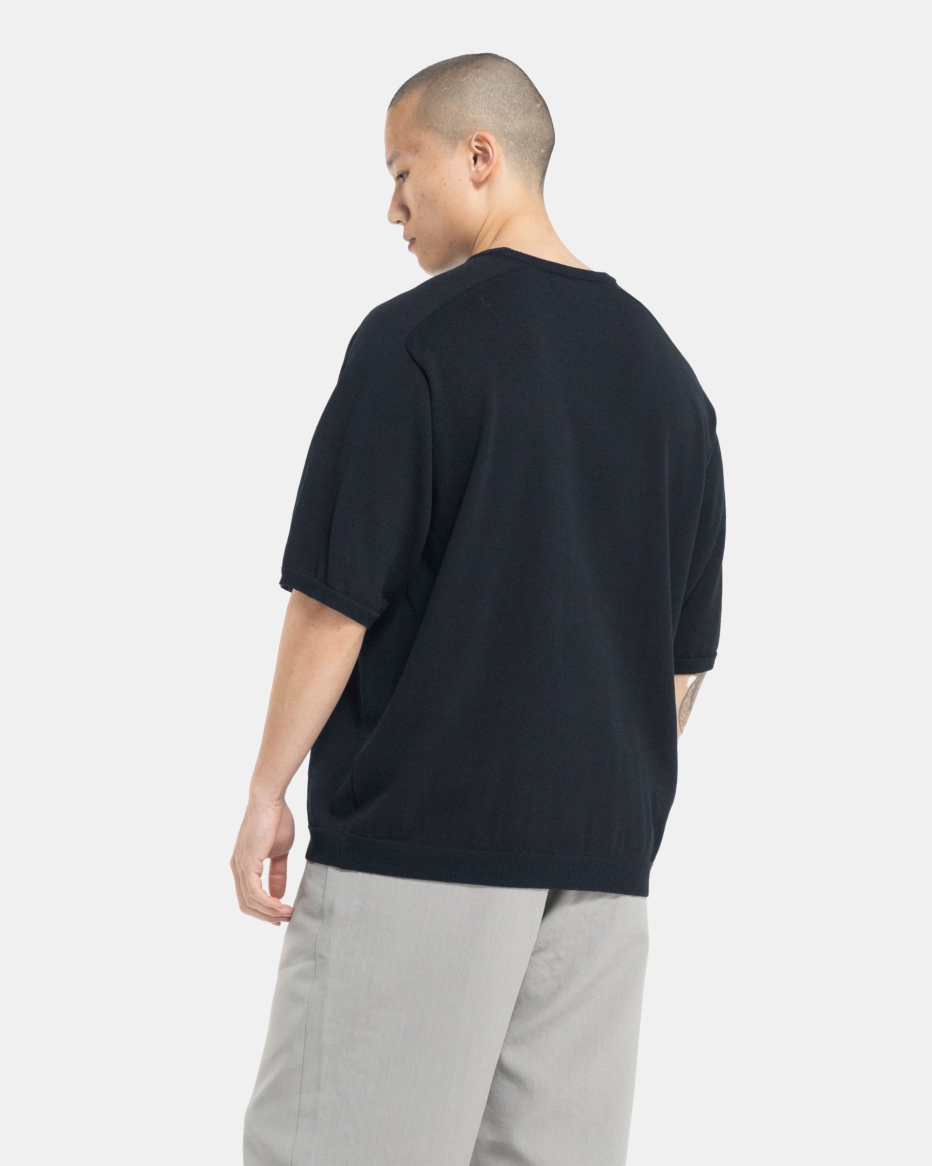 Male model wearing black Still By Hand knit T-shirt on white background