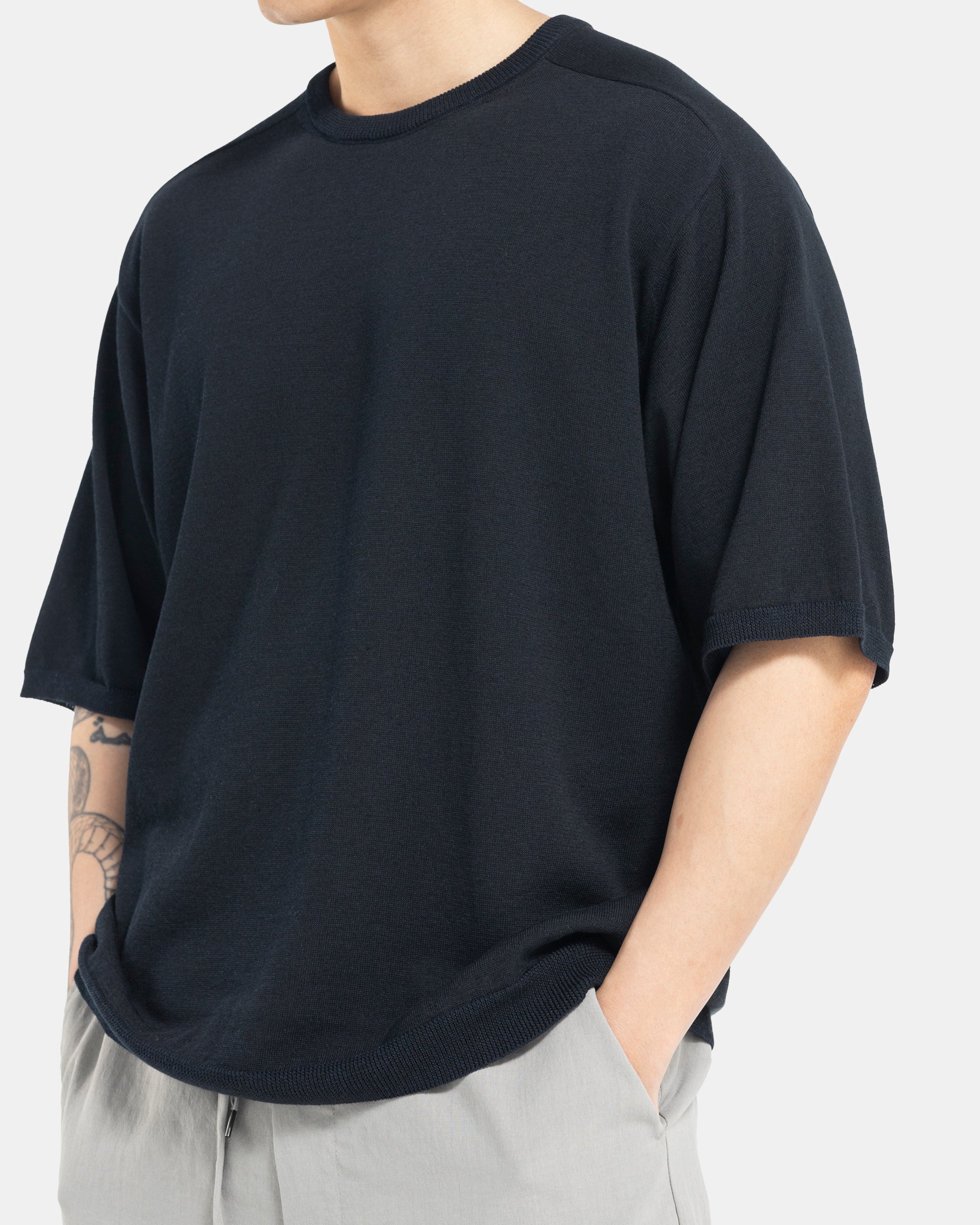 Male model wearing black Still By Hand knit T-shirt on white background