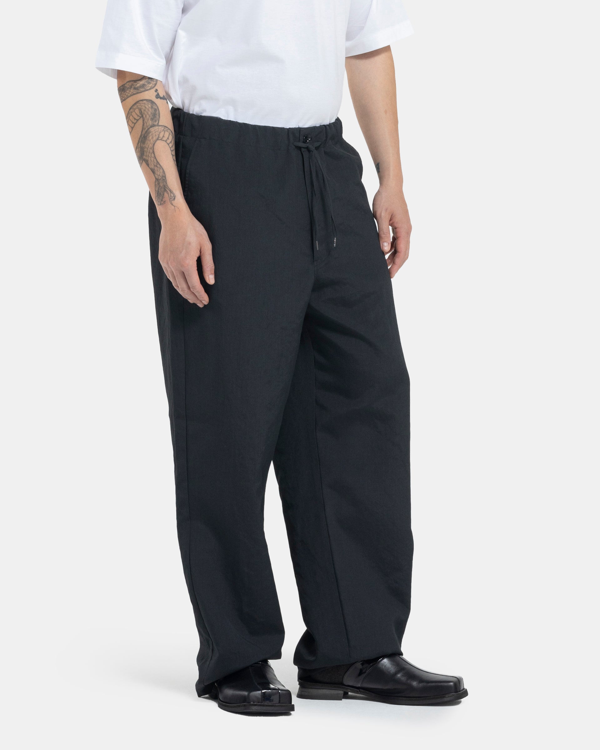 Male model wearing black Still By Hand trousers on white background