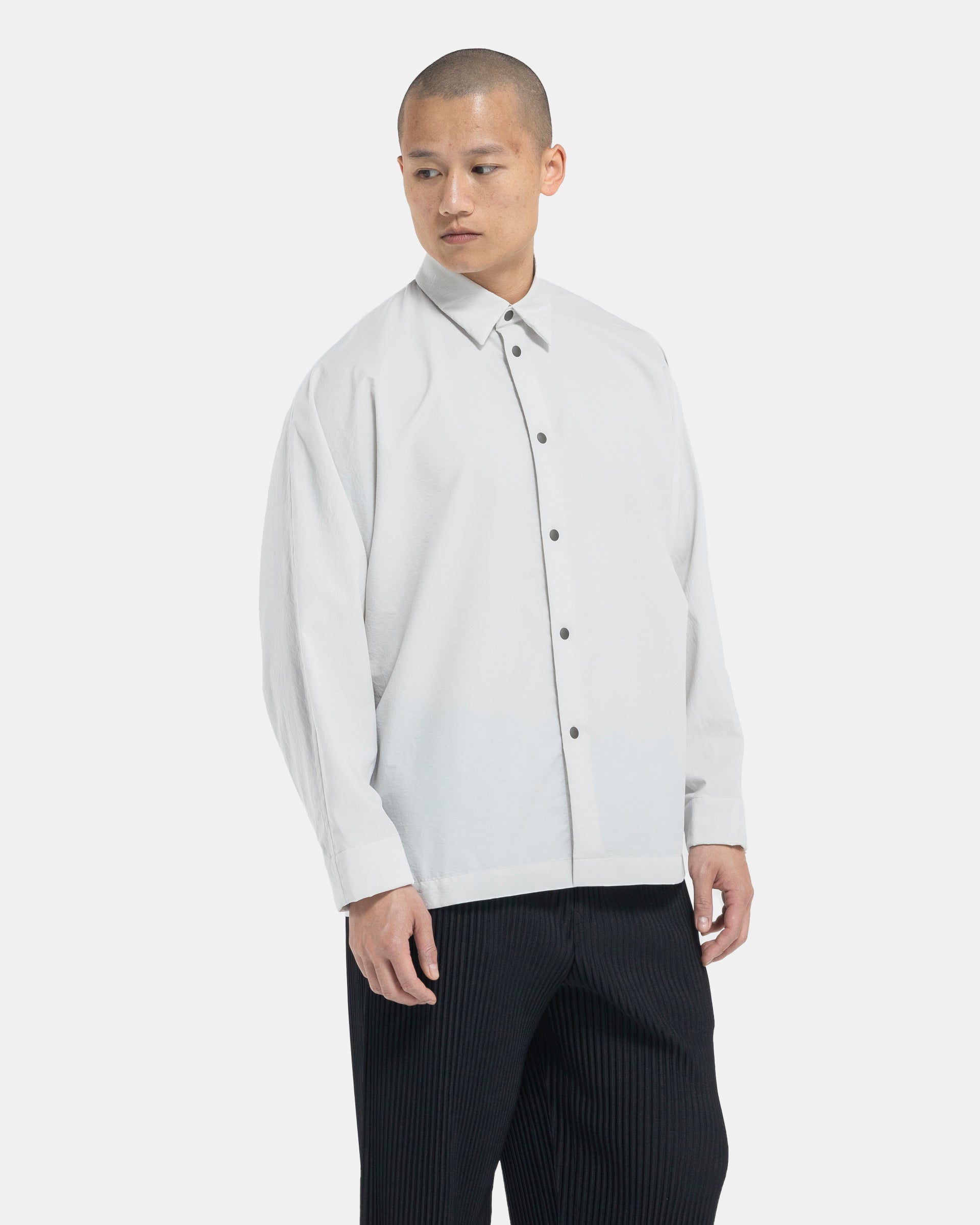 Male model wearing Homme Plissé Issey Miyake white shirt on white background