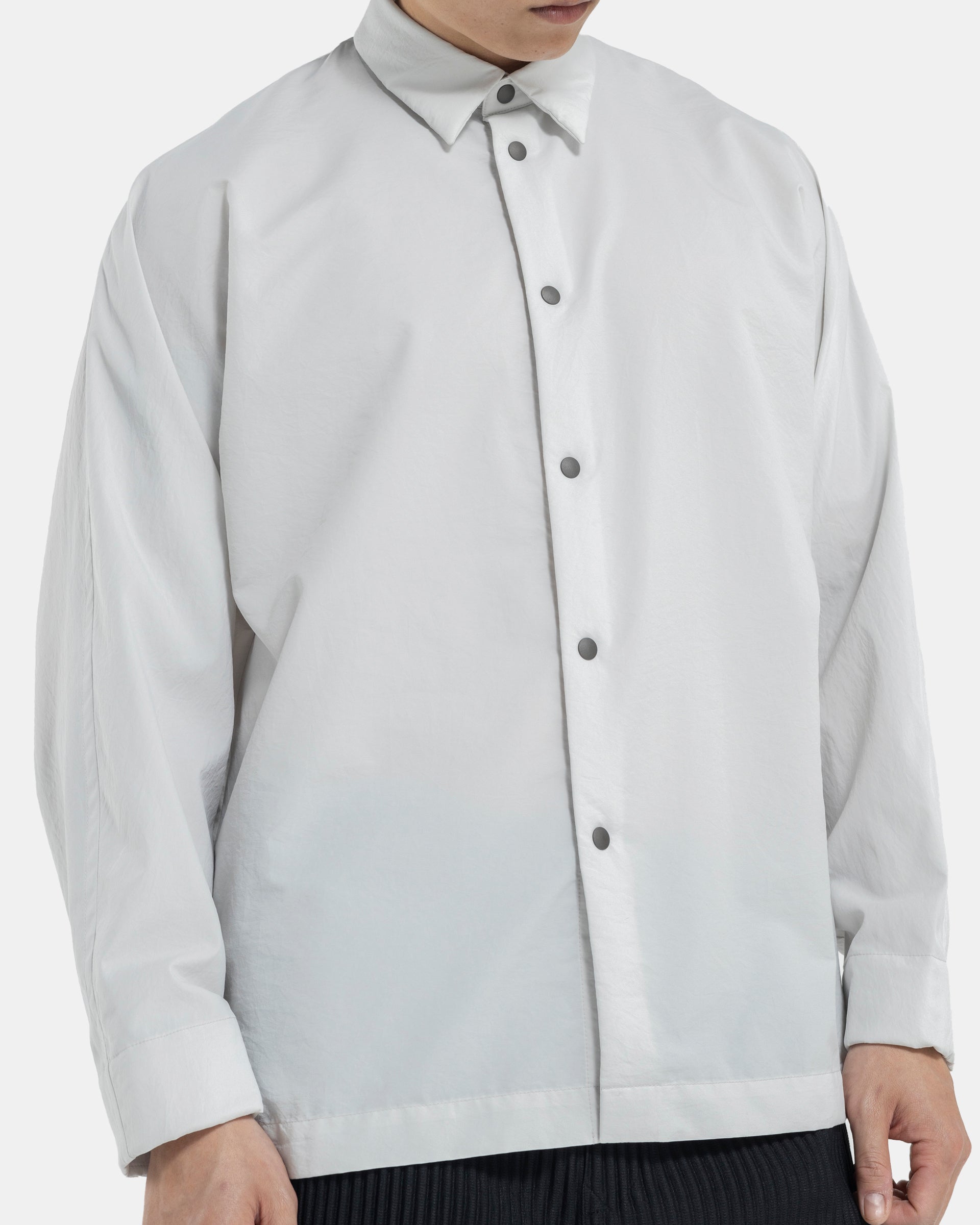 Male model wearing Homme Plissé Issey Miyake white shirt on white background