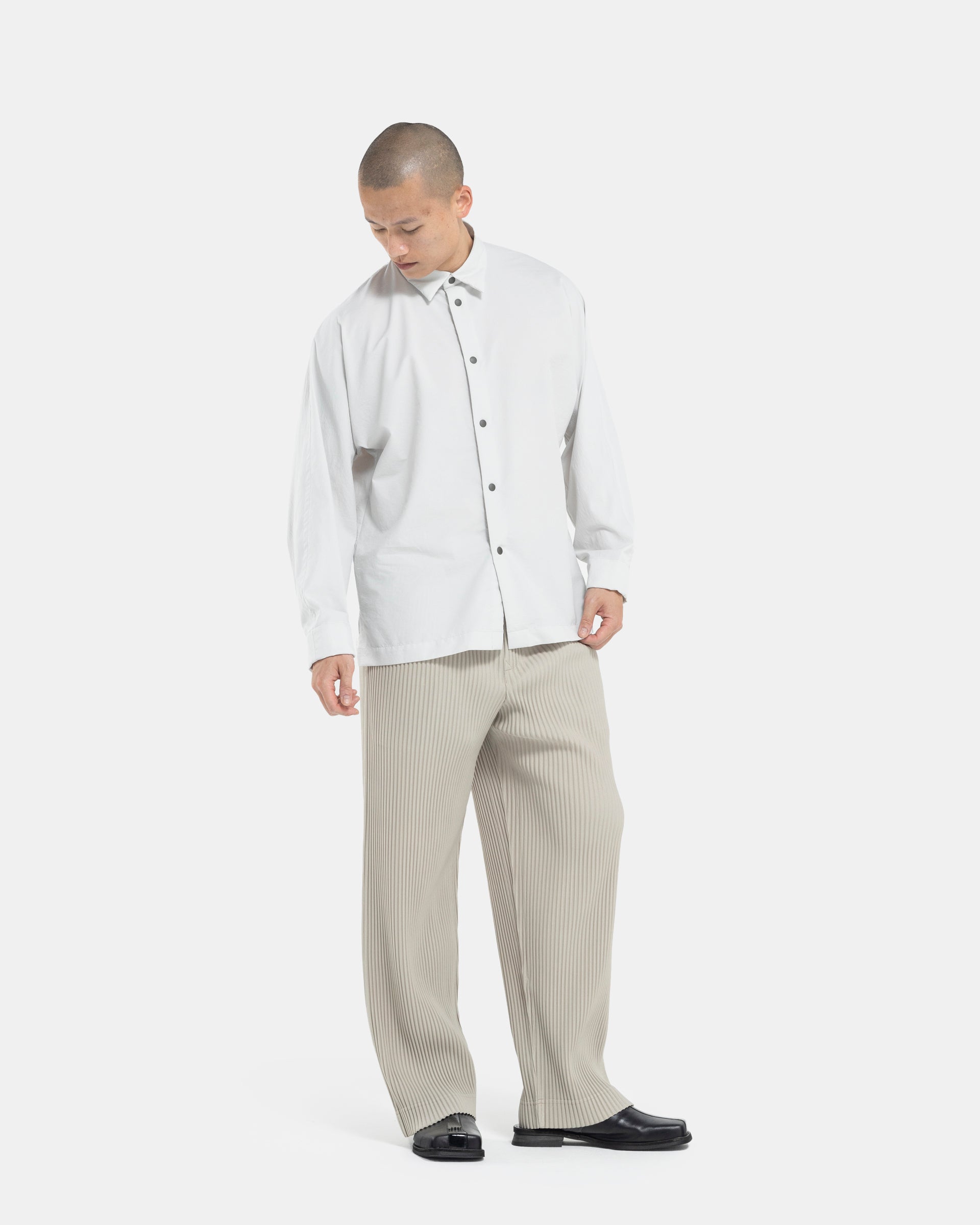 Male model wearing Beige Homme Plissé Issey Miyake pants on white background 