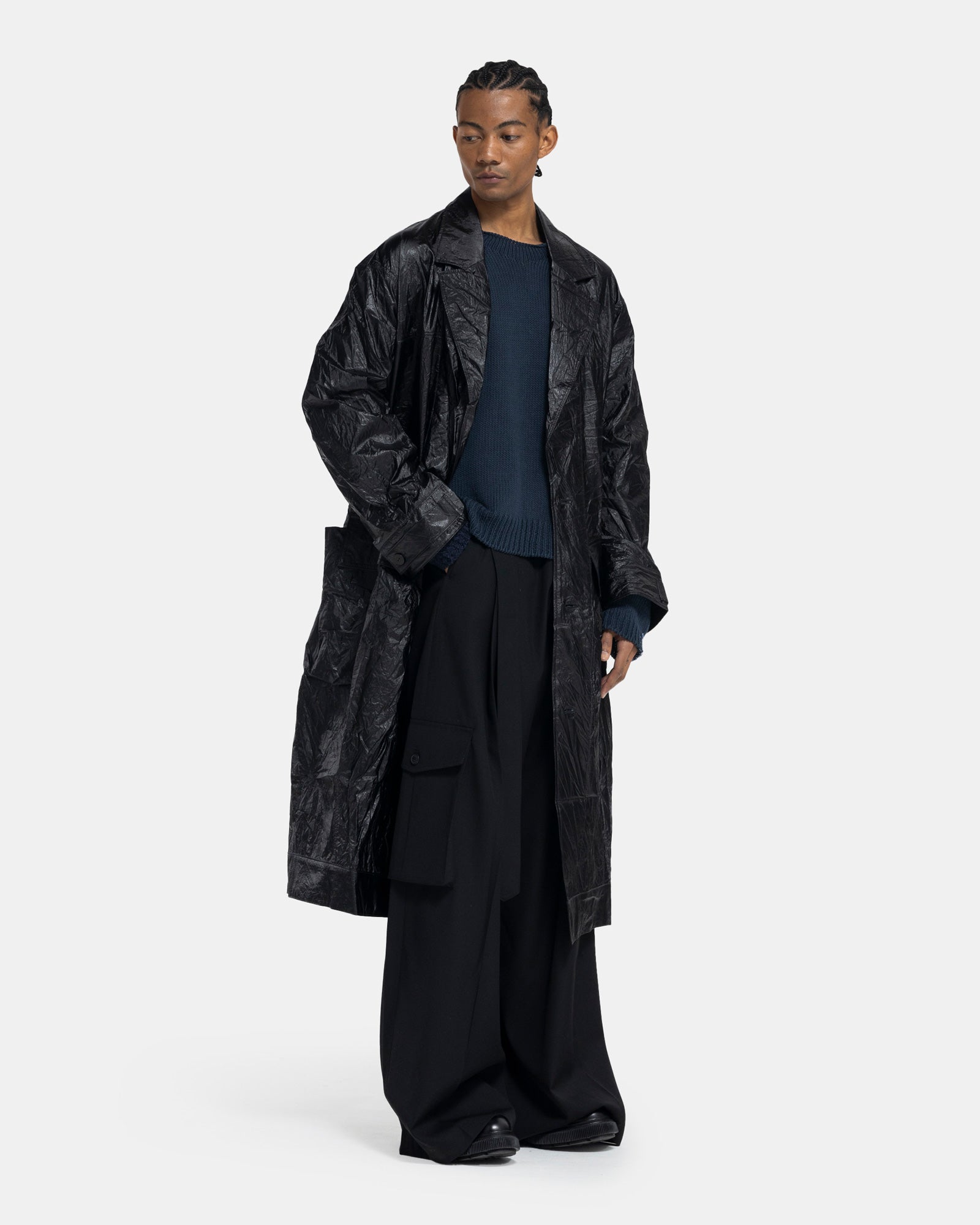Male model wearing ECKHAUS LATTA black crinkle trench on white background