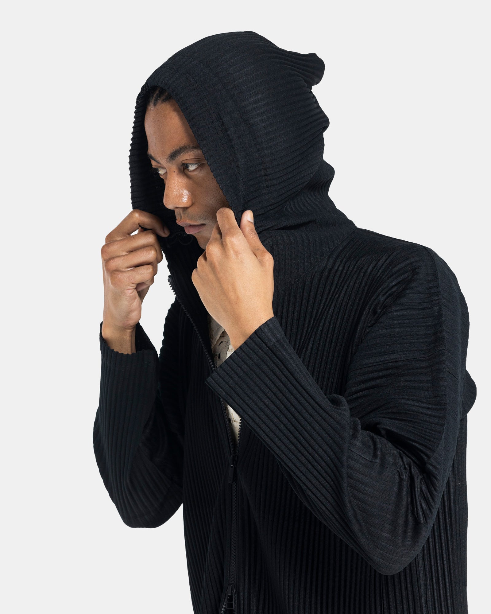 Male model wearing issey miyake homme plissé black pleated hoodie on white background