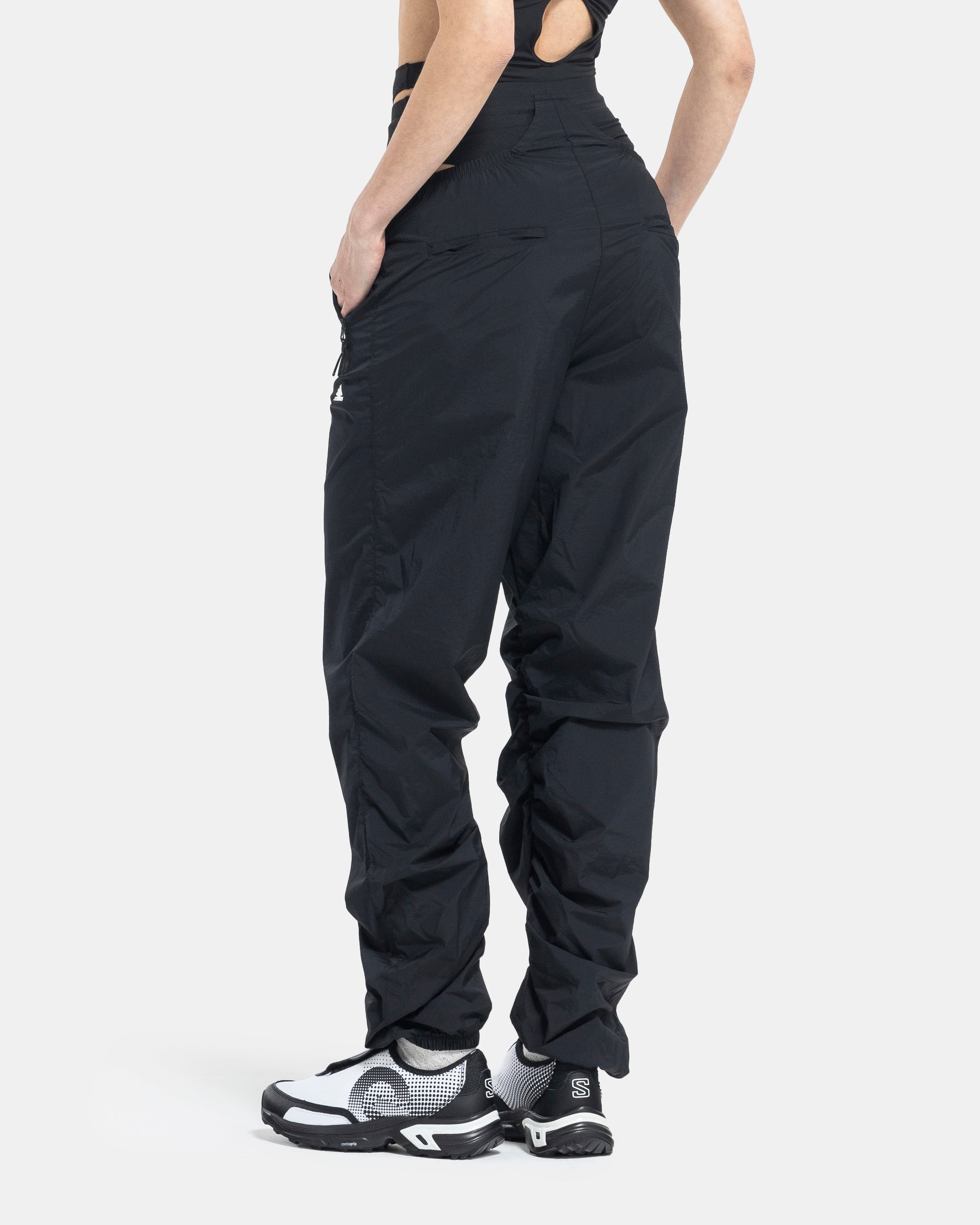 Female model wearing RUI x Adidas Black Track Pants on white background
