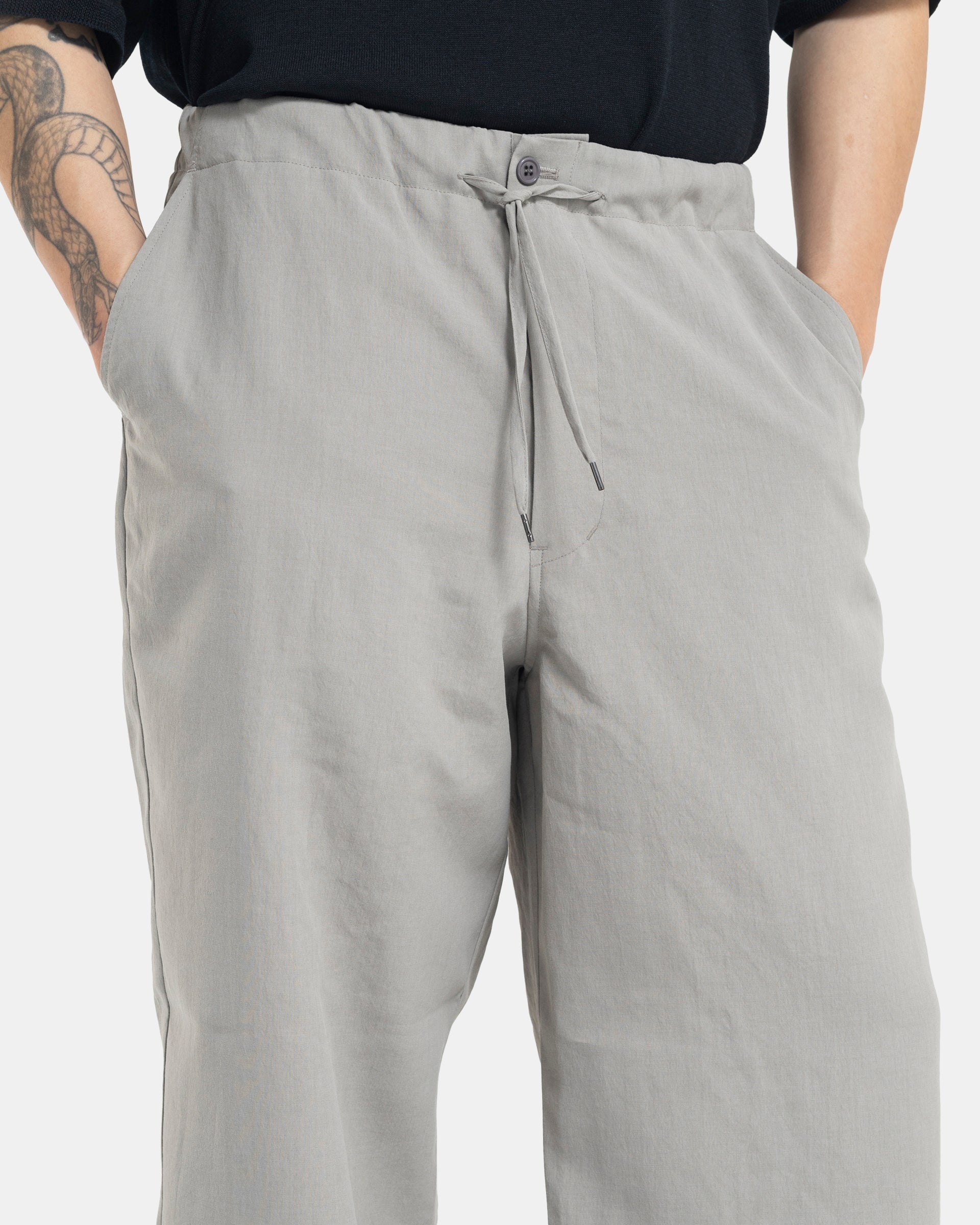 Male model wearing grey Still By Hand trousers on white background