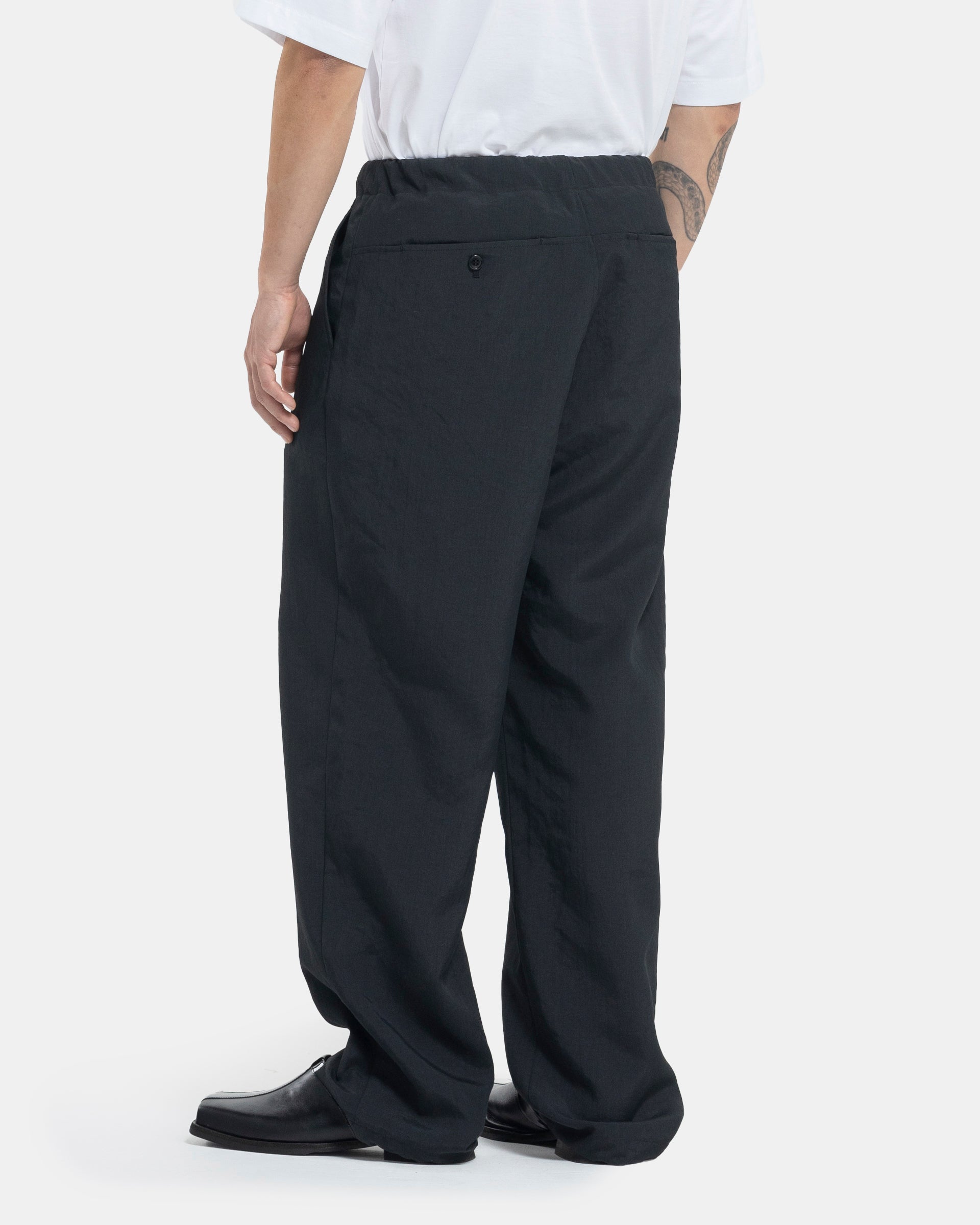 Male model wearing black Still By Hand trousers on white background