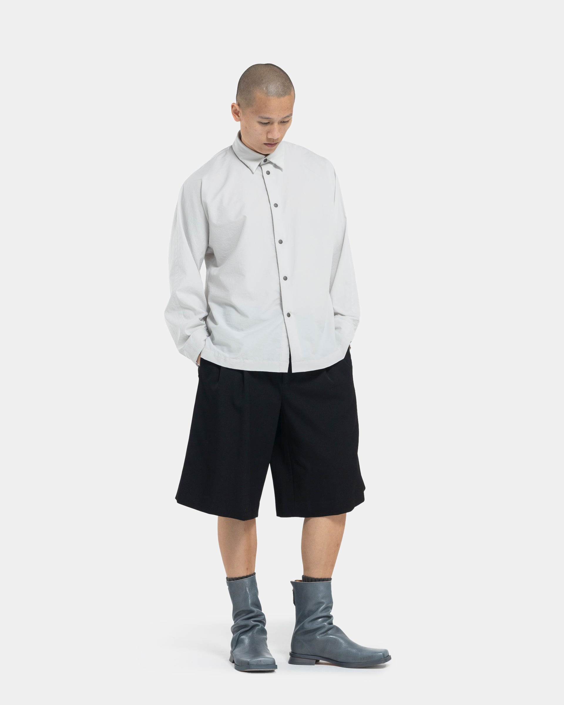 Male model wearing black Comme Des Garçons Homme Plus shorts on white background