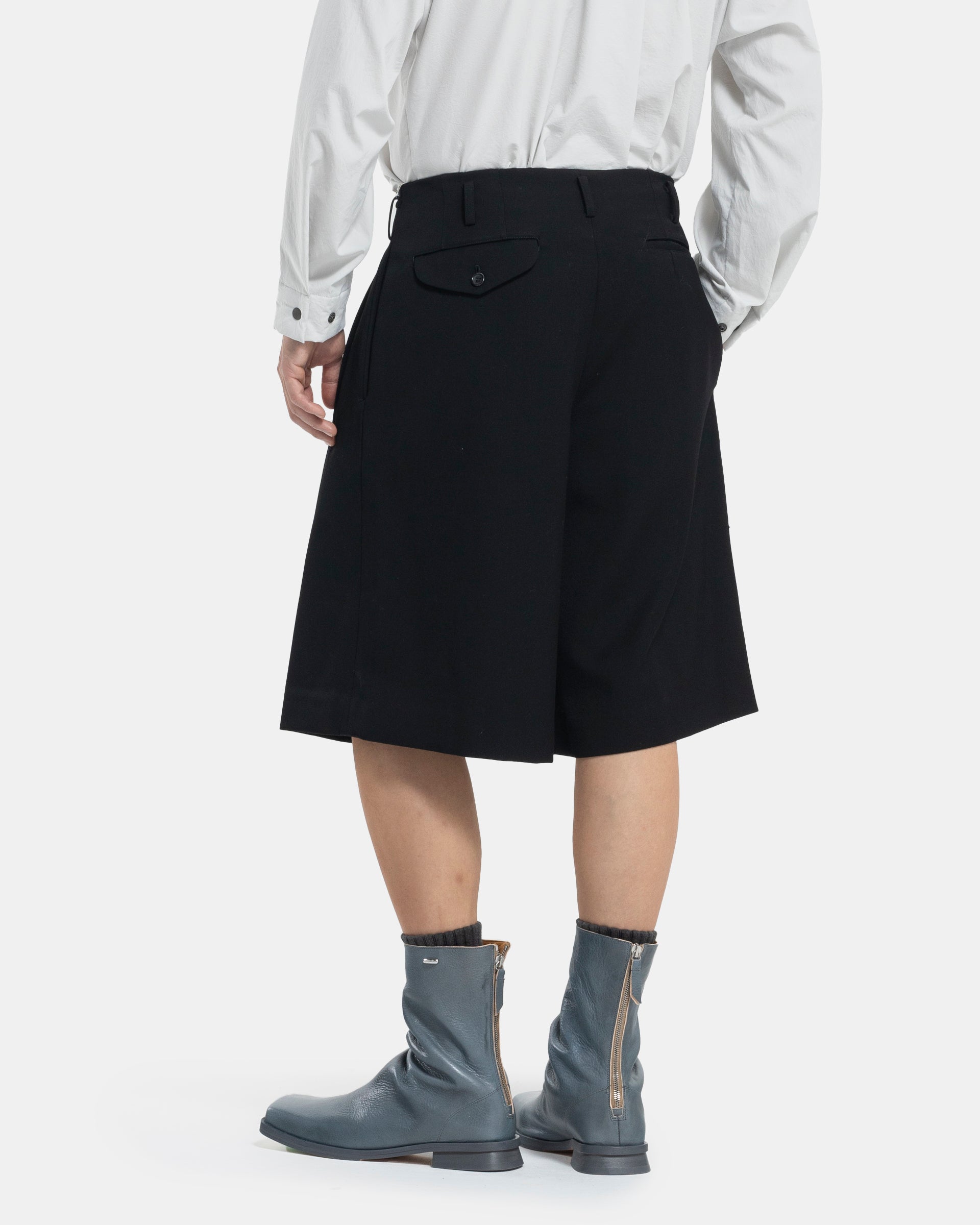 Male model wearing black Comme Des Garçons Homme Plus shorts on white background