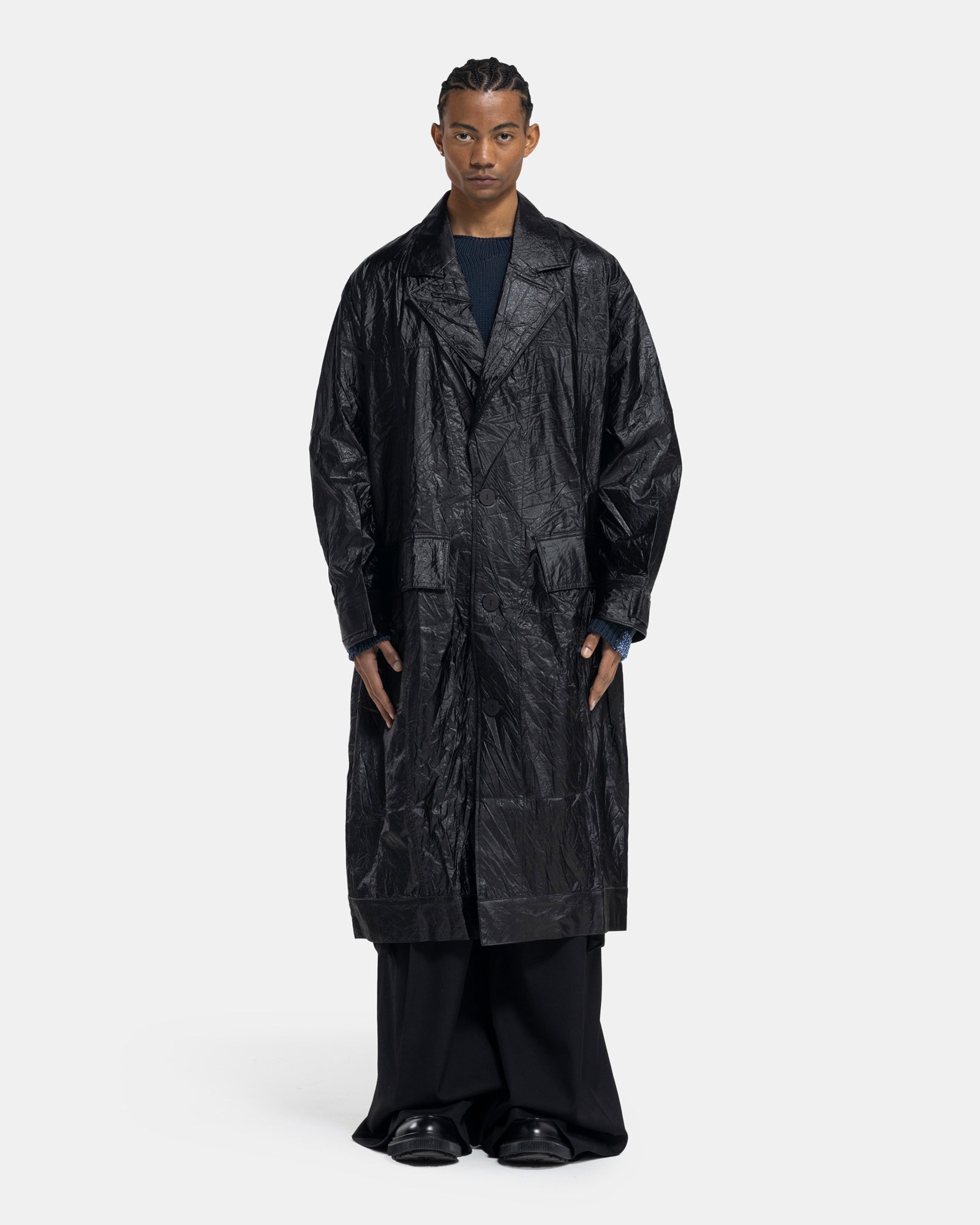 Male model wearing ECKHAUS LATTA black crinkle trench on white background