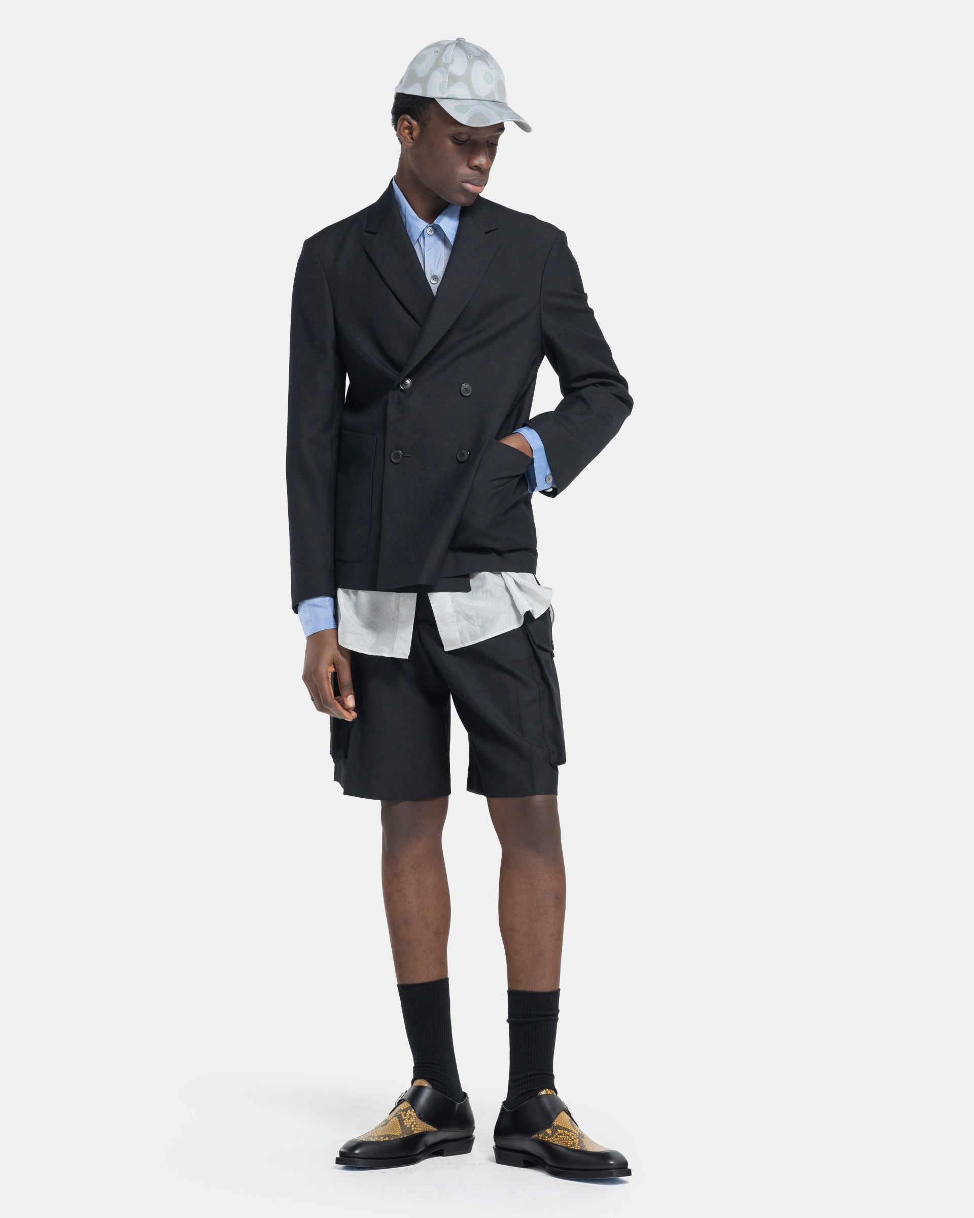 Model wearing Dries Van Noten Piers Bis Shorts in Black on white background