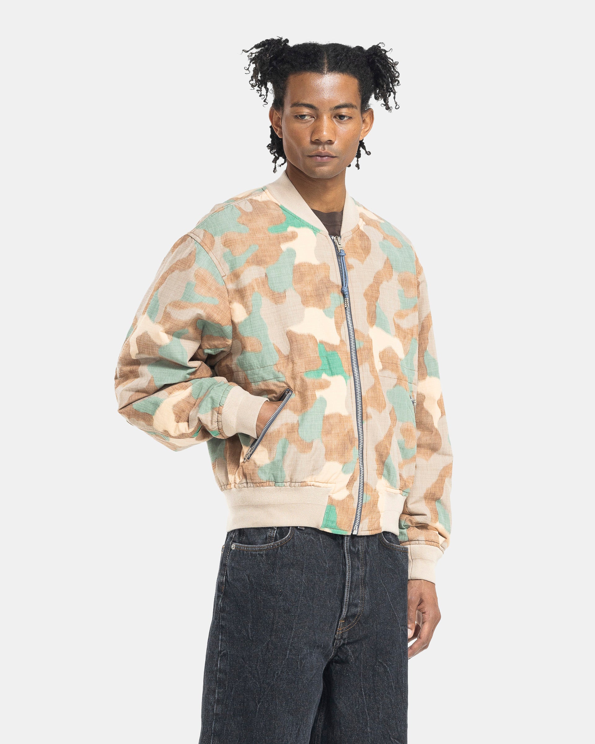 Model wearing Acne Studios Camo Bomber Jacket in Orange & Green on the white background