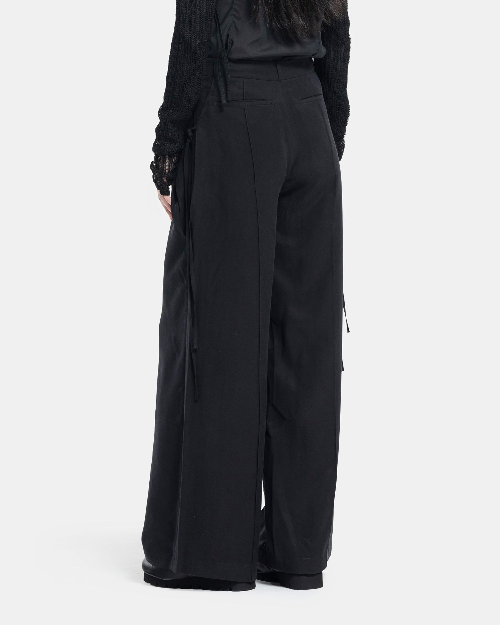 Female model wearing Professor.E black trousers on white background