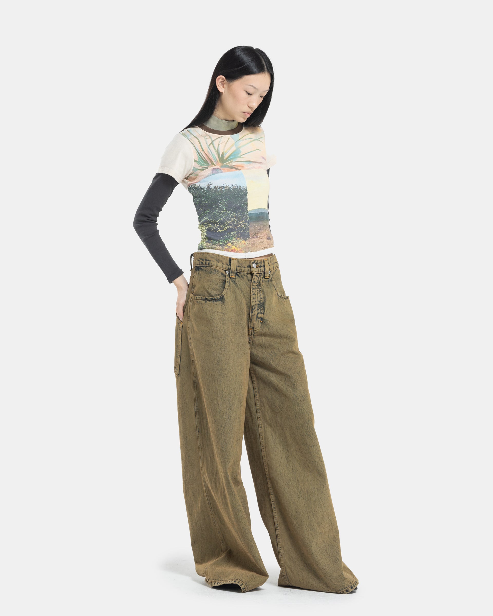 Female model wearing a Eckhaus Latta Lapped Baby Tee with a collage print design and ultra-wide-leg jeans