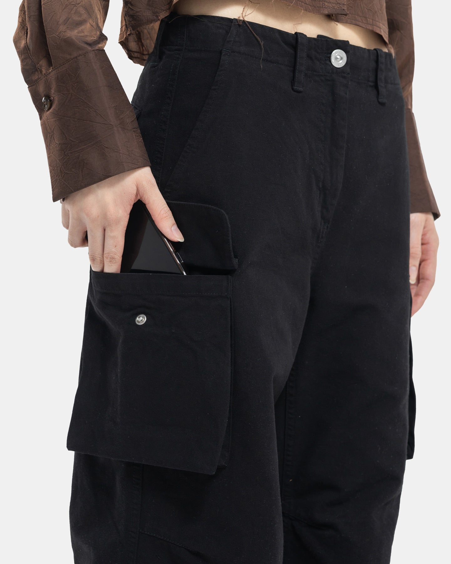 Black Cargo Pants from Our Legacy reaching into pocket on white background