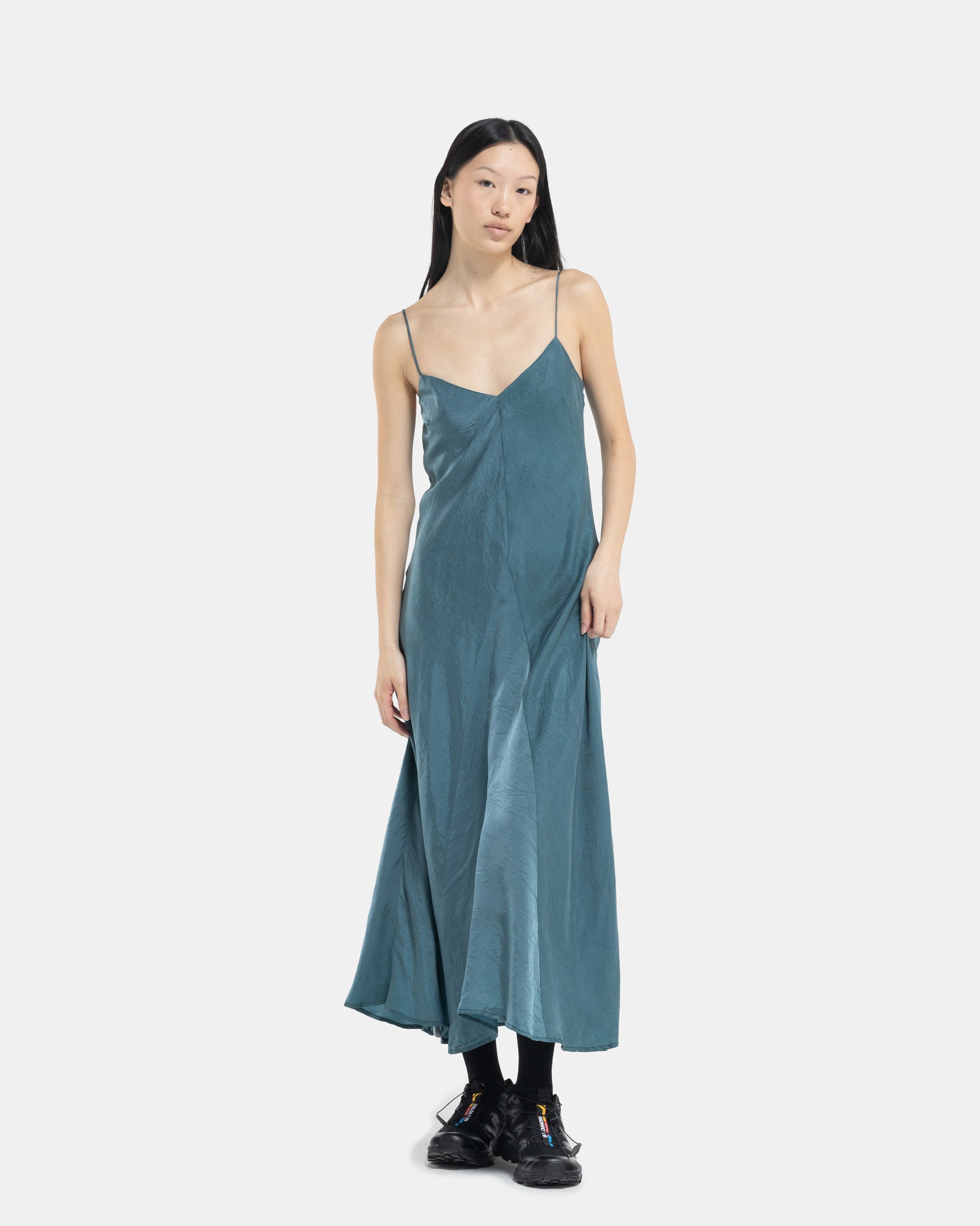 Model wearing blue bias slip dress from Song For The Mute on white background